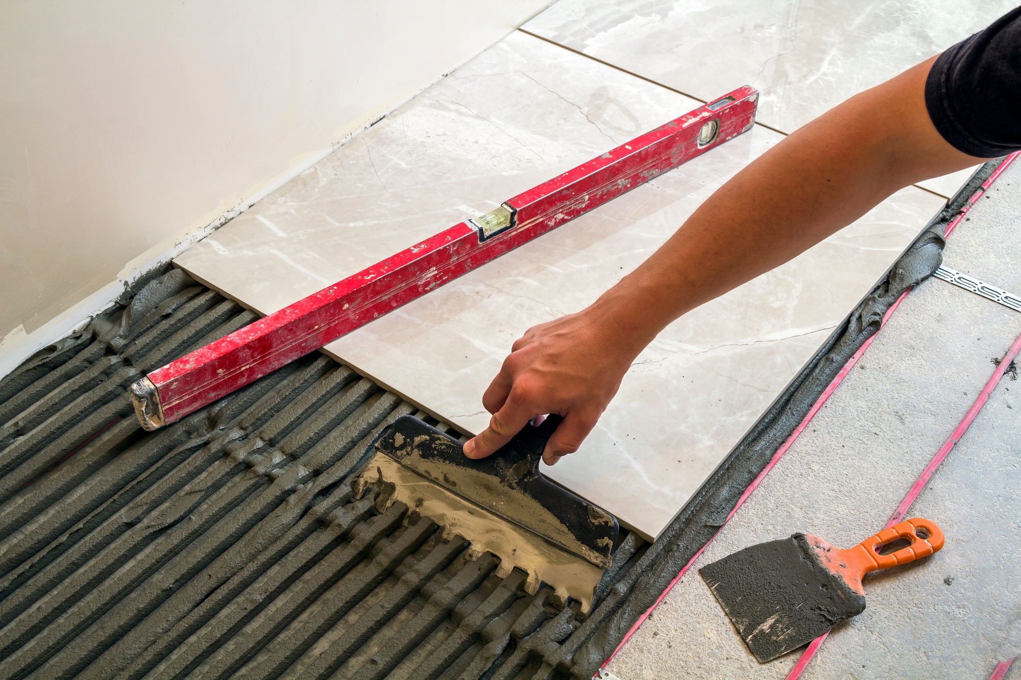 Ceramic tiles and tools for tiler. Worker hand installing floor tiles. Home improvement, renovation