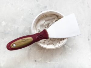 metal spatula on container with putty
