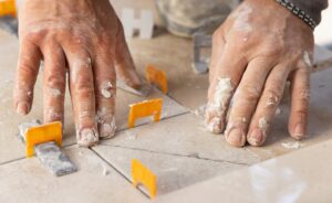 Tiler laying the ceramic tile on the floor with dusty hands. Home renovation or building new house